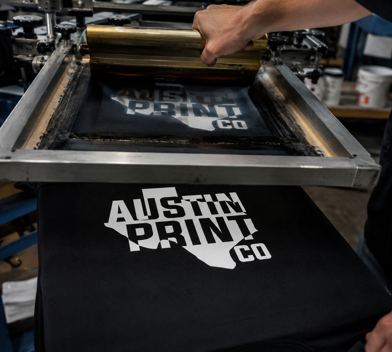 Austin Print Co. screen printing an Austin Print Co. Texas logo tee on the press in our Austin shop